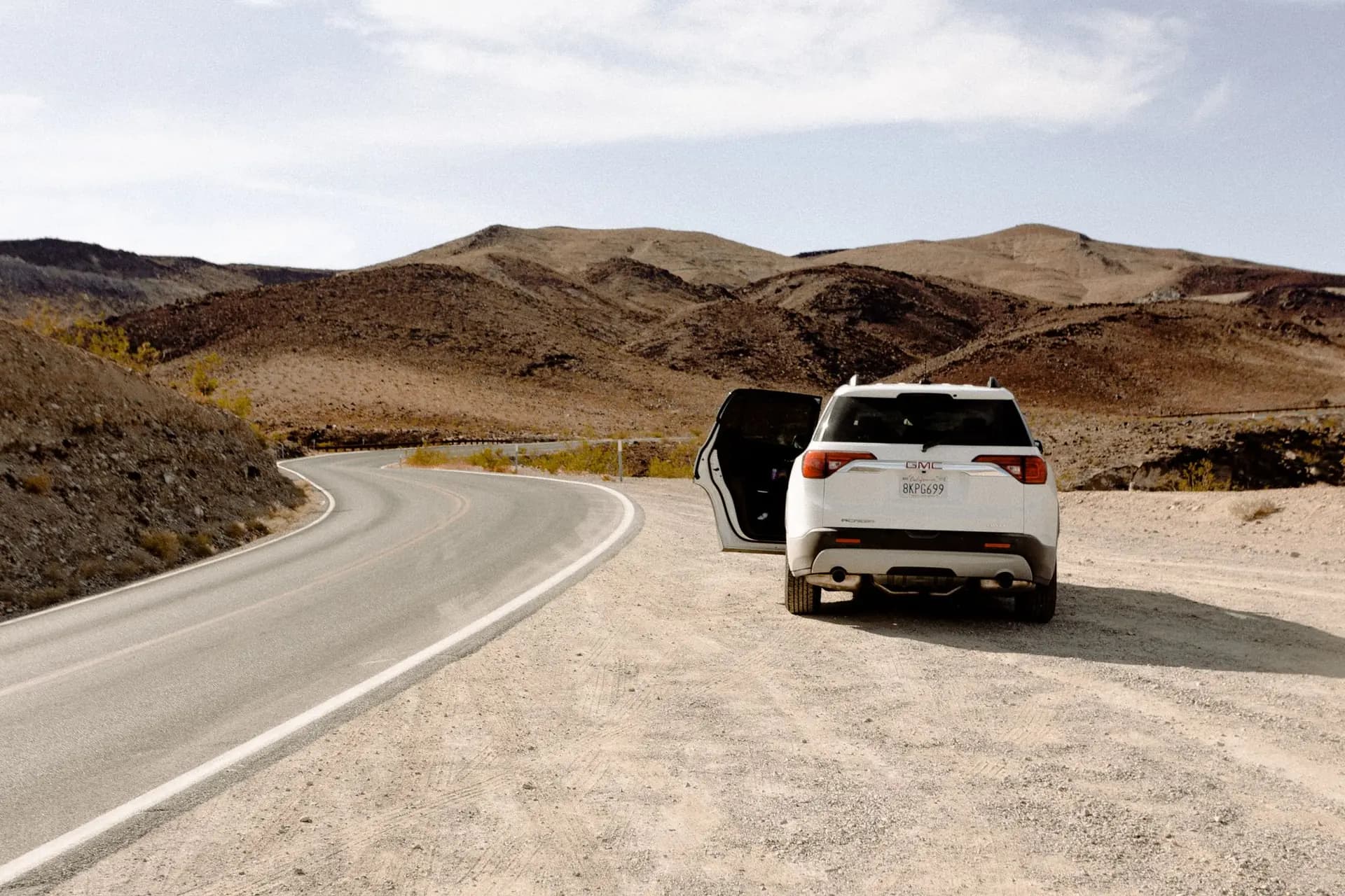 SUV pulled over on a desert road with the rear door open