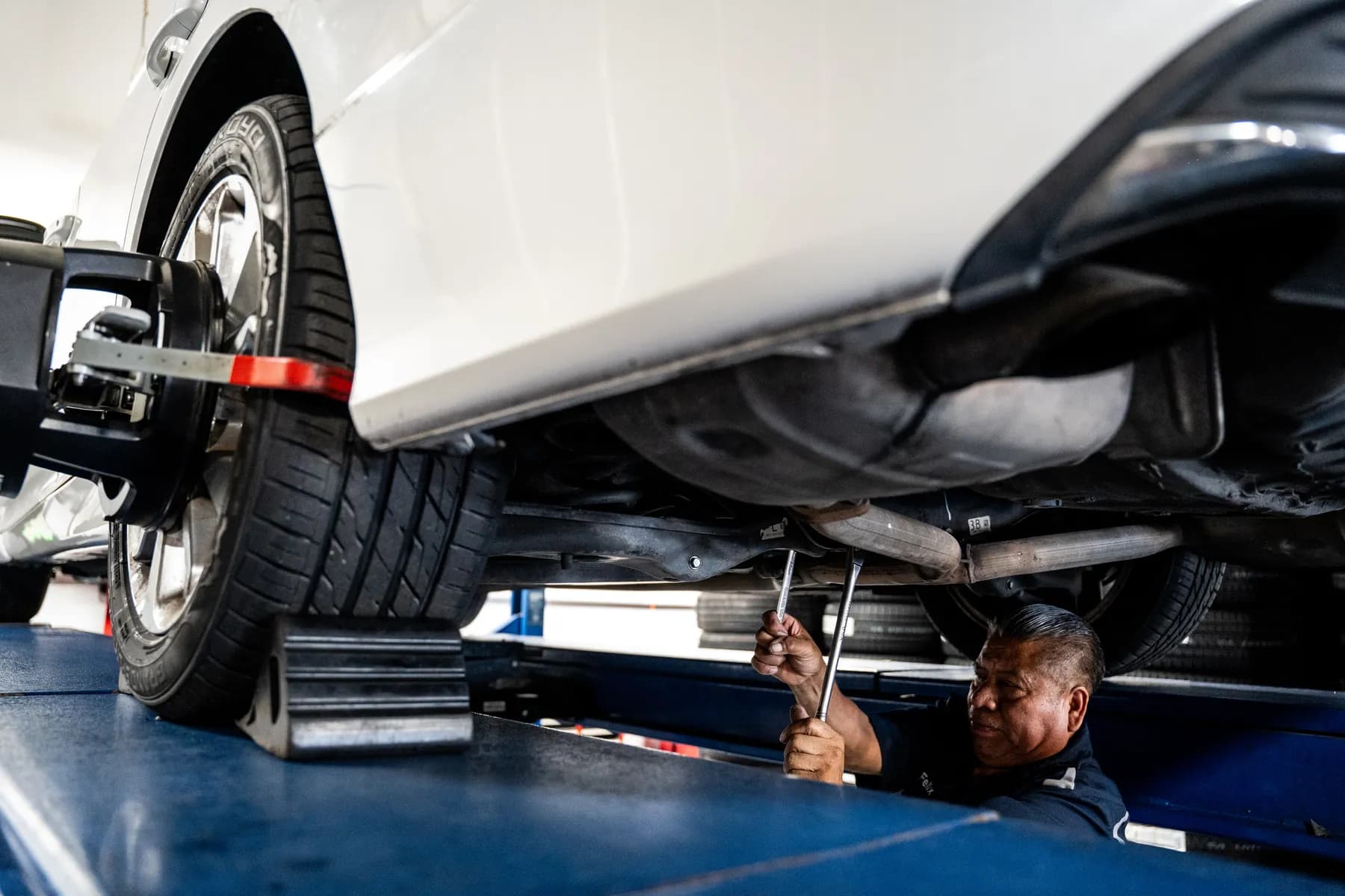 Car raised on the alignment rack with a technician checking the suspension underneath