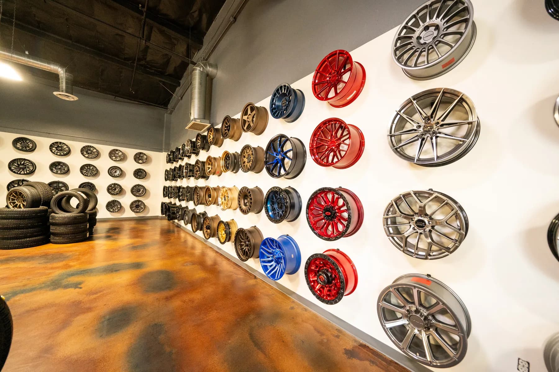 Wall display of aftermarket wheels in red, blue, bronze and silver